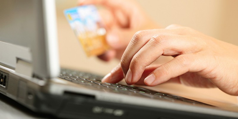 Hands holding credit card and laptop. Shallow DOF